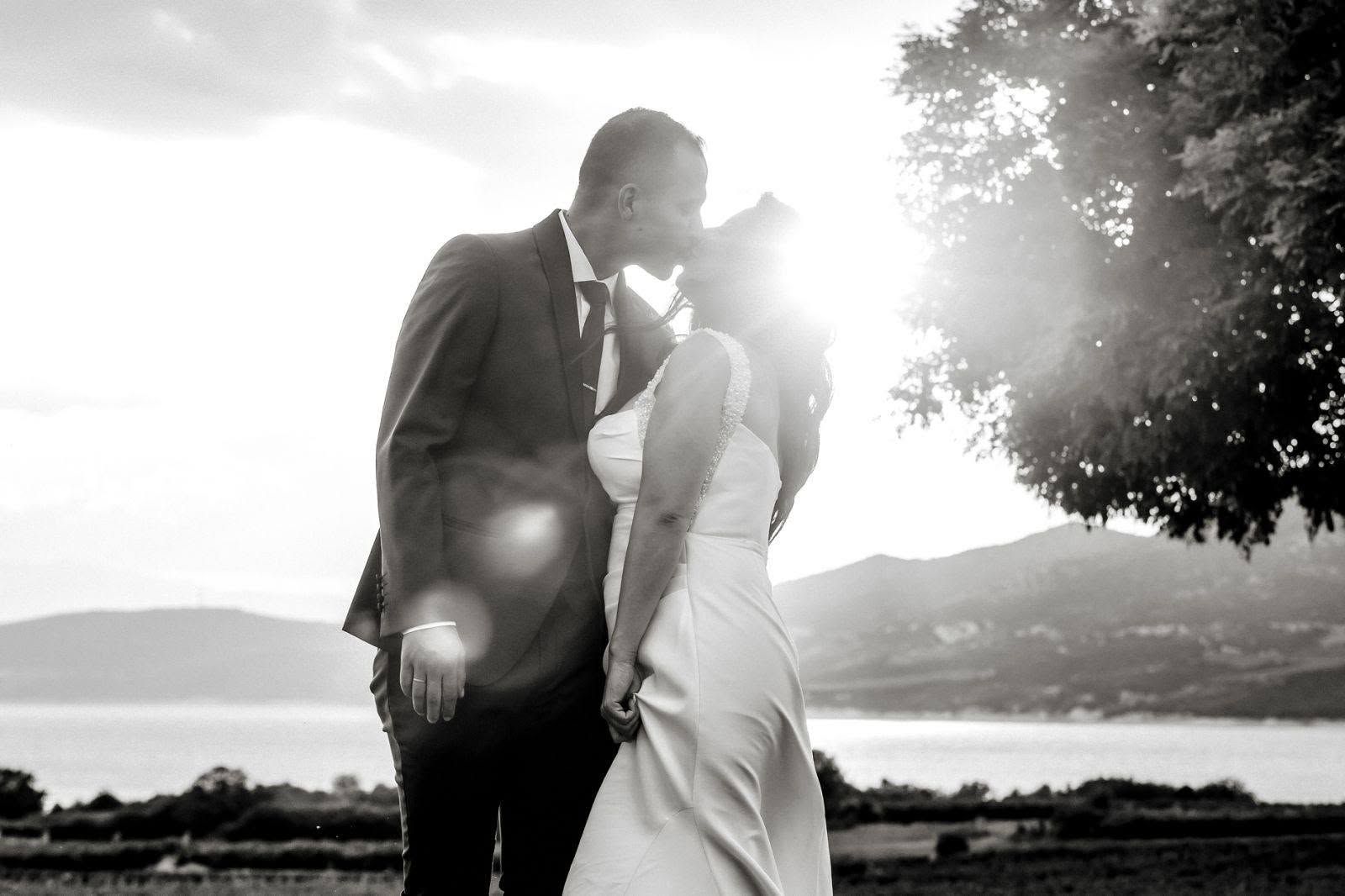 Bride and groom kissing at sunset by the sea
